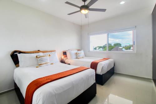 Un dormitorio con dos camas y un ventilador de techo. en The Restful Elephant @ Sabbia D409, en Playa del Carmen