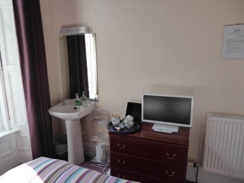 a bedroom with a bed and a television on a dresser at Seashells Guest House in Aberdeen
