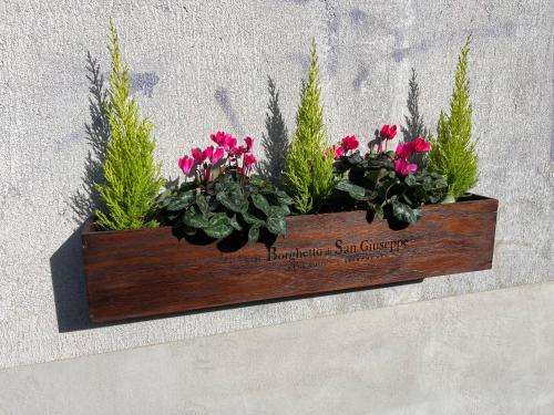 a wooden planter with flowers on a wall at Il Borghetto di San Giuseppe EtnaRooms&Apartments in Nicolosi