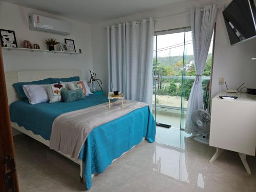 a bedroom with a blue bed and a large window at Casa de Praia frente pro Mar Marataízes in Saco dos Cações