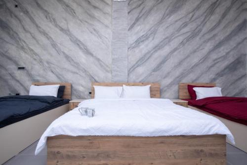 a bedroom with two beds and a concrete wall at Comfortable Slavej Apartment 1 in Sveti Nikole