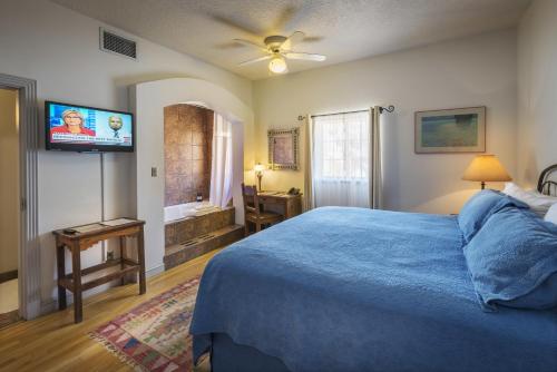 a bedroom with a blue bed and a flat screen tv at Sierra Grande Lodge & Spa in Truth or Consequences