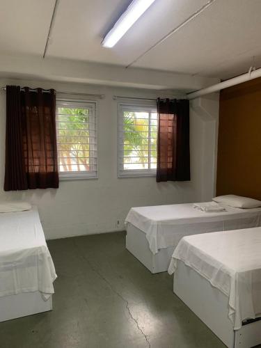 a room with two beds and two windows at Hotel Centro Fashion in Fortaleza