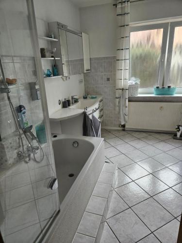 a bathroom with a tub and a sink and a shower at Großes Haus mit Kamin und Garten in Baunatal