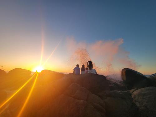 a group of people sitting on a rock watching the sunset at Casa Pepe in Sayulita