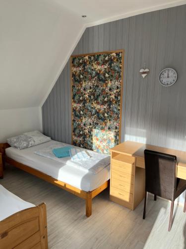 a bedroom with a bed and a desk and a clock at Garis Pension Wesseln 