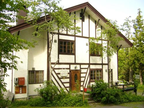a white house with a tree in front of it at Gallery & Lodge Noichigo in Hakuba