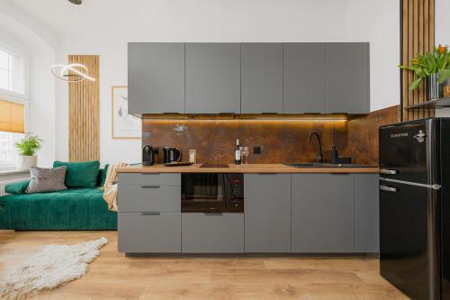 a kitchen with stainless steel appliances and a green couch at Prestige Apartments 19 in Wrocław
