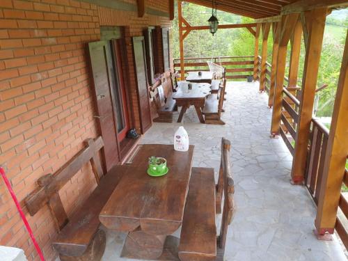 eine Terrasse mit Holzbänken und Tischen auf einem Gebäude in der Unterkunft Kuća za Odmor Naša Priča in Šipovo