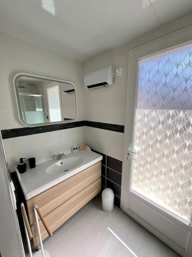une salle de bain avec un lavabo et un miroir dans l'établissement La Villa Azur - Chaleureuse maisonnette avec piscine partagée, à Capbreton