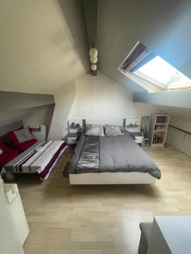 - une chambre mansardée avec un lit et une lucarne dans l'établissement Maison proche JO pour 10/12pers, à Pierrefitte-sur-Seine