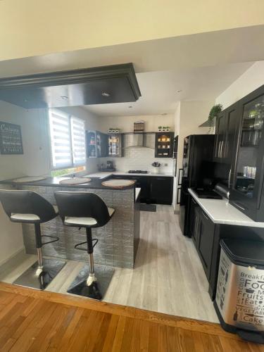 - une cuisine avec des placards noirs et des tabourets de bar dans l'établissement Maison proche JO pour 10/12pers, à Pierrefitte-sur-Seine