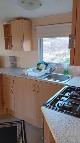 a kitchen with a sink and a stove and a window at Loch Heron View in Newton Stewart