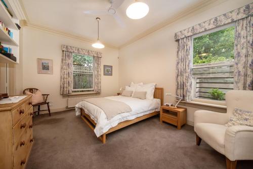 a bedroom with a bed and a chair and a window at Sandringham Royale in Sandringham