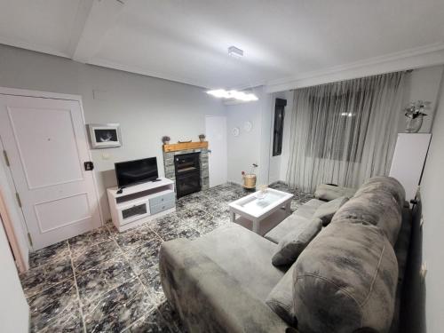 sala de estar con sofá y TV en Coqueto Apartamento, en Martos