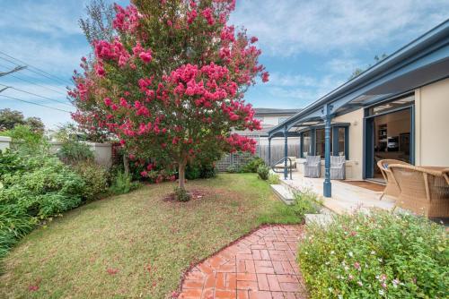 a tree with pink flowers in a yard next to a house at Sandringham Royale in Sandringham