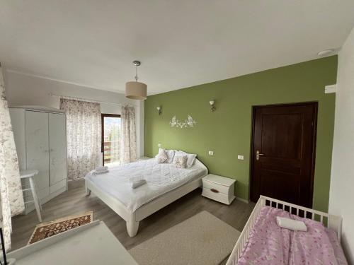 a bedroom with a white bed and a green wall at Casa Bunicii Comarnic in Comarnic