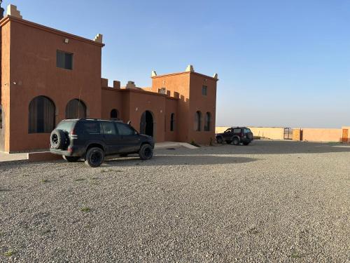 a car parked next to a building in the desert at DAR AL QANASS IMANE in Midelt