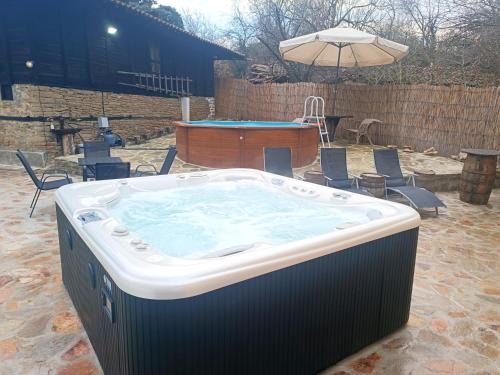 a large hot tub in a yard with a table at Балтовата къща in Medven