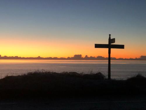 a cross in the middle of a field at sunset at Sea view cottage in Allonby