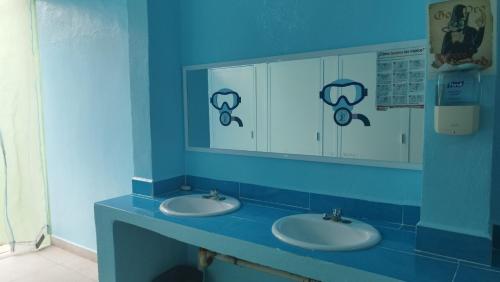 a blue bathroom with two sinks and a mirror at Blue Magic Hostel in Cozumel