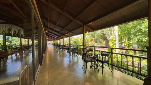 una veranda coperta con tavoli, sedie e alberi di Hotel Raices Esturion a Puerto Iguazú