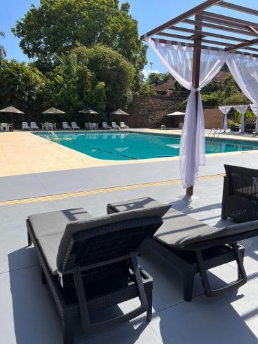 a pool with a table and an umbrella and a chaise lounge at Hotel Raices Esturion in Puerto Iguazú