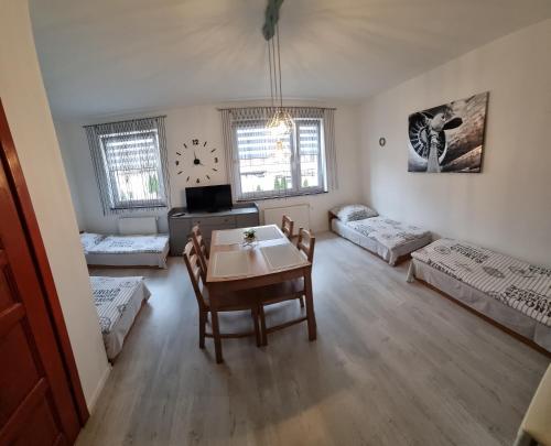 a living room with a table and a room with beds at Noclegi na Łącznej in Świebodzice