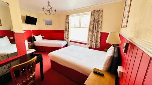 a hotel room with two beds and a window at The Columbia Hotel in Wellingborough