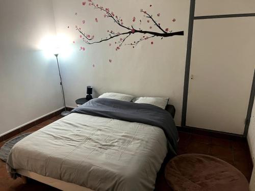 a bedroom with a bed with a tree mural on the wall at Appartement sympa in Fresnes