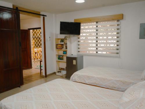 a bedroom with a bed and a window and a television at Casa al pie de la playa con Aire acondicionado y BBQ in Playas
