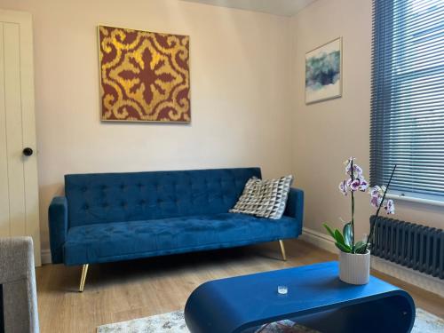 a blue couch in a living room with a table at Stunning 3 bedroom house sleeps up to 6 in Norwood
