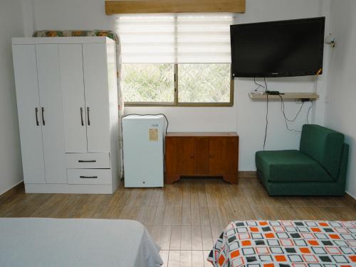 een kamer met een koelkast, een stoel en een televisie bij Casa al pie de la playa con Aire acondicionado y BBQ in Playas