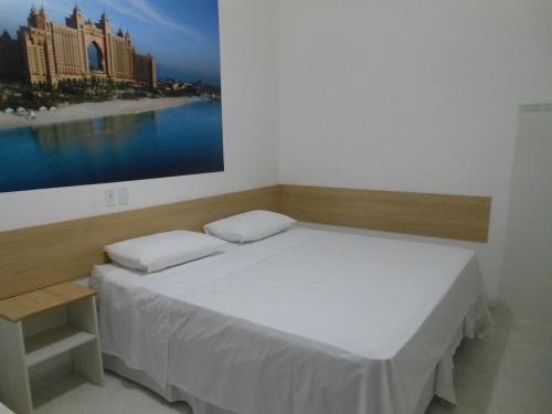 a bed in a room with a large picture on the wall at Pousada Dubai in Taubaté