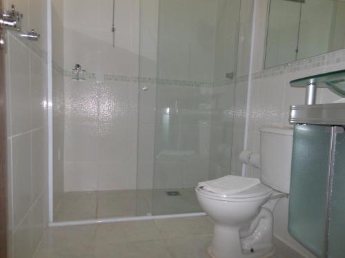 a white bathroom with a shower and a toilet at Pousada Dubai in Taubaté