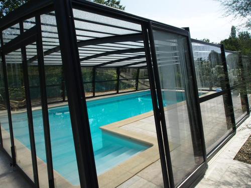 une maison en verre avec une piscine et une pergola dans l'établissement A L'Orée du Bois, à Baron