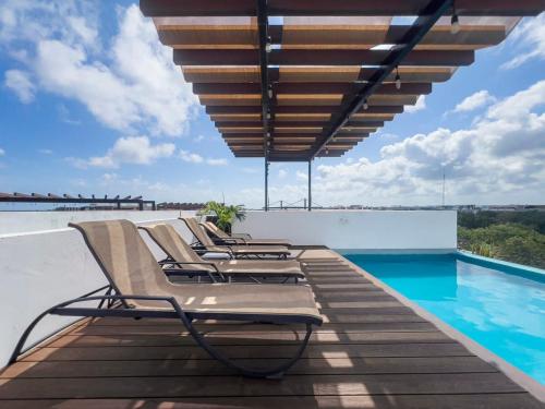 a group of lounge chairs sitting on a wooden deck next to a swimming pool at Escape to Tulum, Luxury Apt, Pool & pet friendly in Tulum