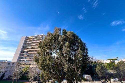 un grand arbre devant un grand bâtiment dans l'établissement Antibes - 4 people - Parking, à Antibes