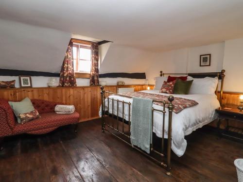 a bedroom with a bed and a chair and a window at Runnymede in Tewkesbury