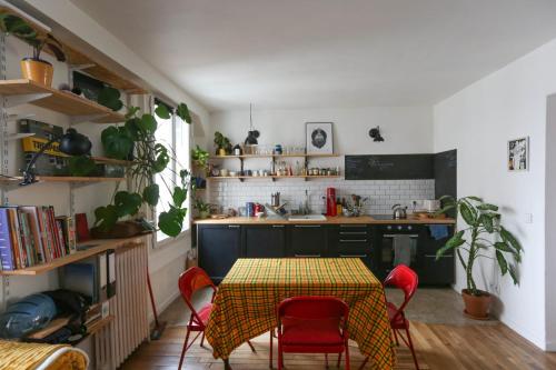 uma cozinha com uma mesa com cadeiras vermelhas e uma cozinha com um lavatório em Bright apartment in Aubervilliers em Aubervilliers