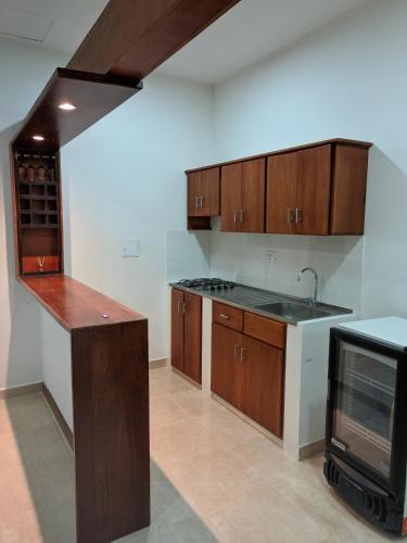 Apartamento Confort في أربوليتيه: مطبخ بدولاب خشبي ومغسلة وتلفزيون