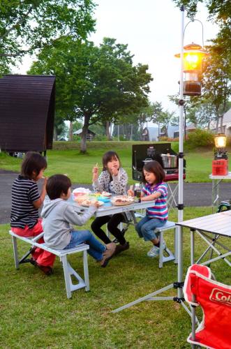 un grupo de niños sentados alrededor de una mesa de picnic en New Greenpia Tsunan Campsite - Vacation STAY 41973v en Akinari