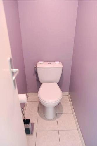 La salle de bains est pourvue de toilettes blanches dans un mur violet. dans l'établissement Le pieds dans l'eau - Direct sur la mer, au Guilvinec