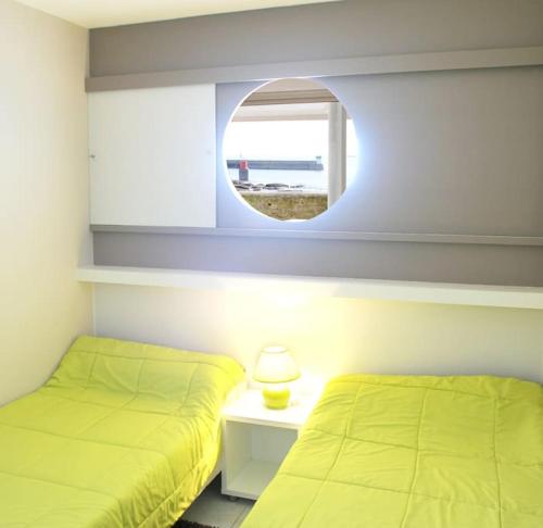Un dormitorio con dos camas y un espejo. en Le pieds dans l'eau - Direct sur la mer, en Le Guilvinec