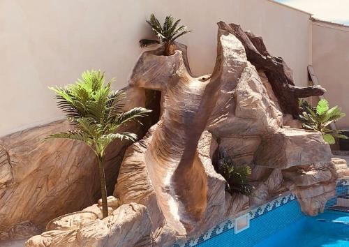 een kamer met een neprotswand naast een zwembad bij Villa 4P piscine avec toboggan et cascade in Bessan