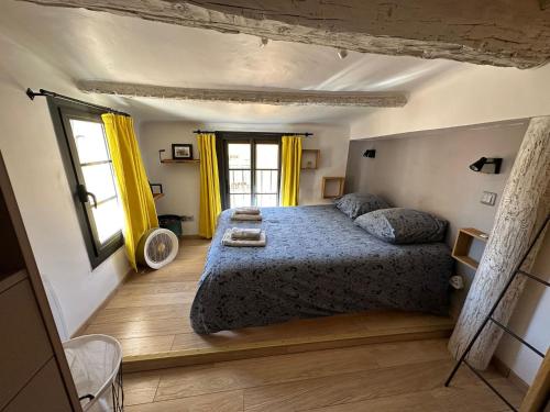 sypialnia z łóżkiem z niebieską kołdrą i żółtymi zasłonami w obiekcie Toits Vieil - Appartement de charme avec terrasse d'exception Aix-en-Provence w Aix-en-Provence