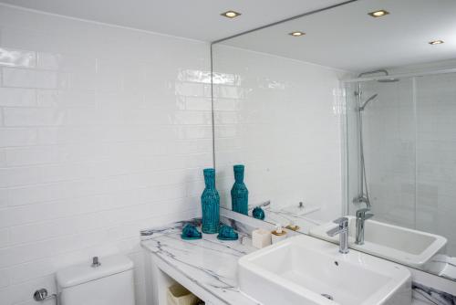 a white bathroom with a sink and a mirror at To see the sea apartment in Sesimbra