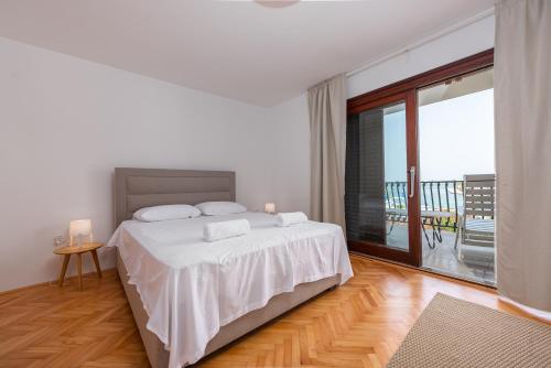 een witte slaapkamer met een bed en een balkon bij Villa LUMA Sukošan - house by the sea in Sukošan