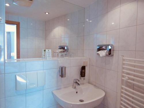 a white bathroom with a sink and a mirror at Pension Hexenkessel in Wernigerode