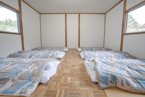 fila de camas en una habitación con ventanas en Shinei Kiyosato Campsite - Vacation STAY 42245v, en Hokuto